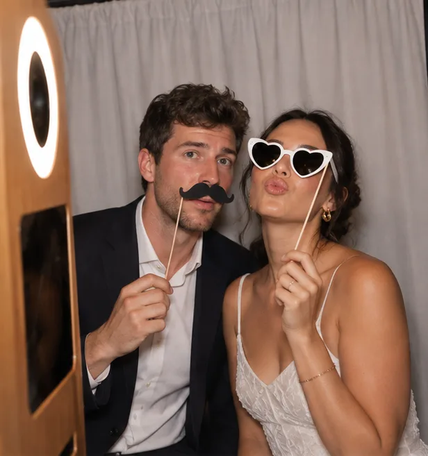 A couple posing with a mustache and heart-shaped glasses
